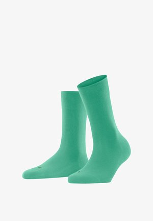 Green cotton socks with a smooth texture, ribbed cuffs, and a tapered shape. Features minimal branding on the underside.
