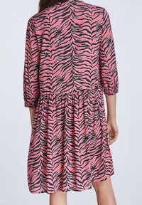 Robe à rayures roses et noires avec manches trois-quarts, taille froncée et longueur au genou, en tissu léger.