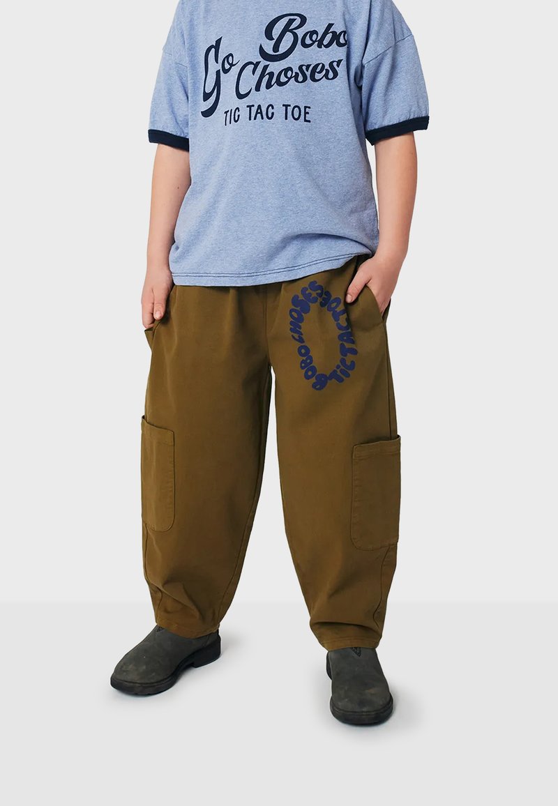 Blue graphic t-shirt with white text and dark blue accents, paired with loose brown cargo pants featuring side pockets and printed lettering.