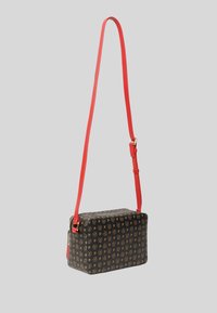 Borsa rettangolare nera con motivo a logo dorato ripetuto, manico rosso e dettagli in hardware dorato. Chiusura a zip nella parte superiore.