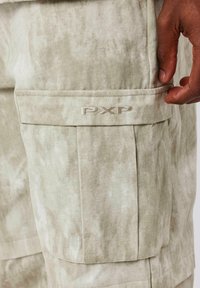 Cargo shorts in lichtbeige stof met een gestructureerd, gemêleerd patroon. Voorzien van een zijzak met geborduurd "PXP" logo.