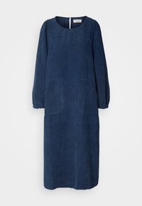 Robe en velours côtelé bleu marine à manches longues avec encolure ronde, poignets élastiqués, poches plaquées devant et fermeture boutonnée au dos.