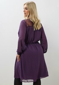Vestido de gasa morado con textura de puntos, yugo de encaje transparente, mangas largas y cintura elástica, que llega a la mitad de la pantorrilla.
