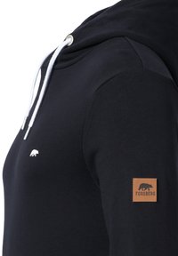 Navy blue hoodie with white drawstrings, a small white bear logo on the chest, and a brown leather patch on the left sleeve. Soft texture.