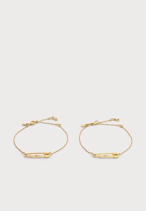 Zwei filigrane Goldkettenarmbänder mit rechteckigen Namensschild-Anhängern, graviert mit "Beatriz" auf weißem Hintergrund.