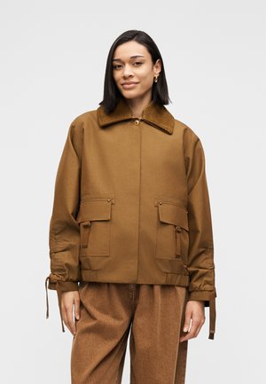 Braune Jacke mit einem Cord-Kragen, zwei Fronttaschen und verstellbaren Manschetten. Hergestellt aus robustem Material, mit lockerem Schnitt und Reißverschluss.