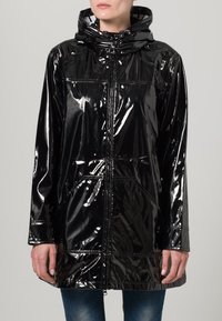 Musta, kiiltävä sadetakki, jossa on huppu, vetoketju edessä ja kaksi sivutaskua; takissa on sauman detaljit ja hieman väljä istuvuus.