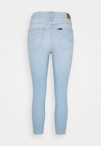 Jeans skinny de denim azul claro con una textura suave, con una cintura alta, dos bolsillos traseros y una etiqueta de marca de cuero marrón en la cinturilla.