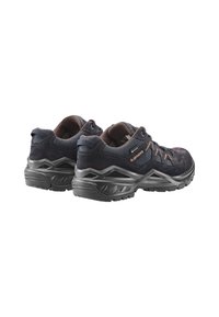 Un paio di scarpe da trekking nere e marroni con suole spesse e lacci, posizionate con i talloni rivolti in avanti su uno sfondo bianco.