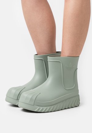 Botas de goma verdes hasta el tobillo con un acabado texturizado, suela acanalada y detalle de logo en relieve en el lado exterior. Altura corta para facilitar su uso.