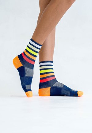 Marineblaue Socken mit bunten Streifen in Gelb, Rot und Orange, einem strukturierten Muster und orangefarbenen Akzenten an Zehe und Ferse.