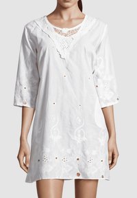 Vestido blanco con escote de encaje, mangas 3/4, bordado floral y un detalle de botones en el dobladillo, hecho de una tela ligera.