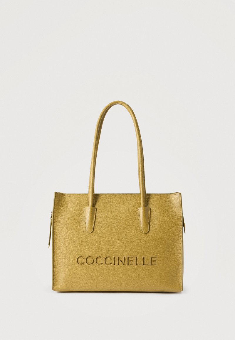 Κίτρινη δερμάτινη τσάντα tote με διπλές λαβές και ανάγλυφο λογότυπο "COCCINELLE" στο μπροστινό μέρος, καθαρό λευκό φόντο.
