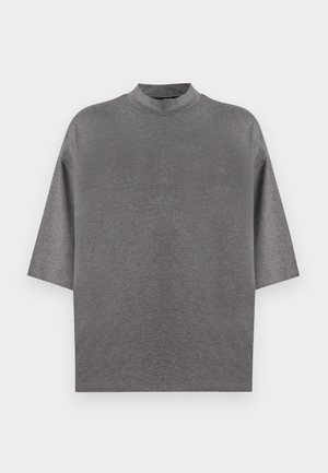 Hall halli lühikeste varrukatega pluus kõrge kaelusega. Valmistatud pehmest, siledast kangast. Omab lahtist istuvust ja langenud õlgu, ilma mustrite või aksentideta.