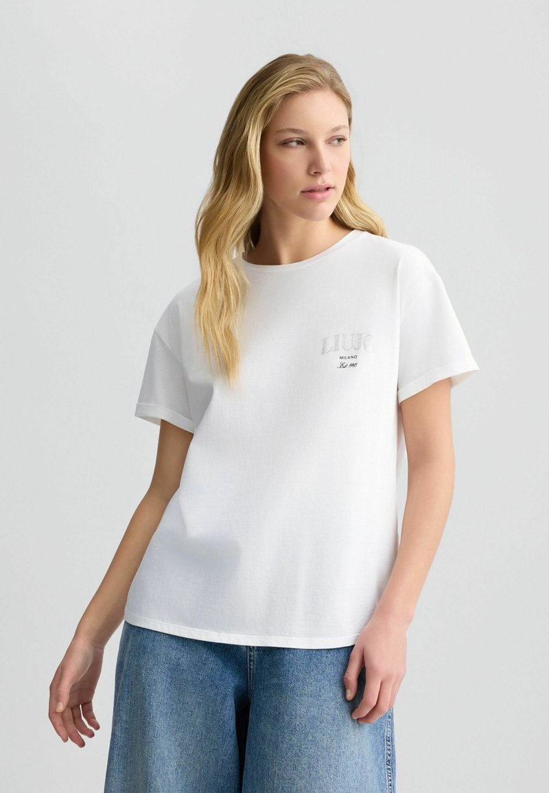 T-shirt en coton blanc à manches courtes, col rond et logo gris sur la poitrine. Présente une coupe décontractée et une texture douce.