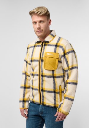 Fleecejack in crème met een gele en marineblauwe ruitpatroon. Beschikt over een gele borstzak en een zwarte rits. Zachte textuur en casual design.