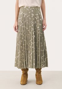 Plissé olijfgroene rok met zilveren loofdruk, gestructureerde stof en elastische tailleband, gecombineerd met lichtbruine suède enkellaarsjes.