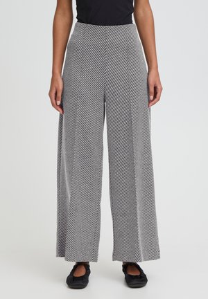 Bukser med vide ben i et sort-hvidt diagonalt stribet mønster, med høj talje og ben i lige snit. Materialet virker tekstureret og let.