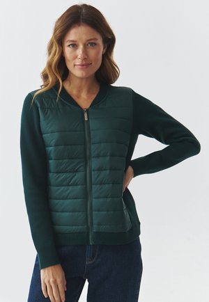 Grüne Zip-up Strickjacke mit einem gesteppte Vorderseite und figurbetonten Ärmeln. Weicher Stoff, gerippte Bündchen und Kragen, mit einem schlanken Design.