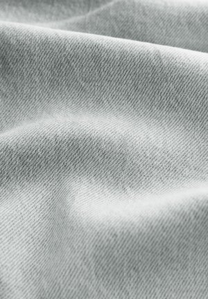 Hellgrauer Stoff mit einem strukturierten, diagonalen Webmuster. Das Material wirkt weich und leicht reflektierend und zeigt glatte Falten.