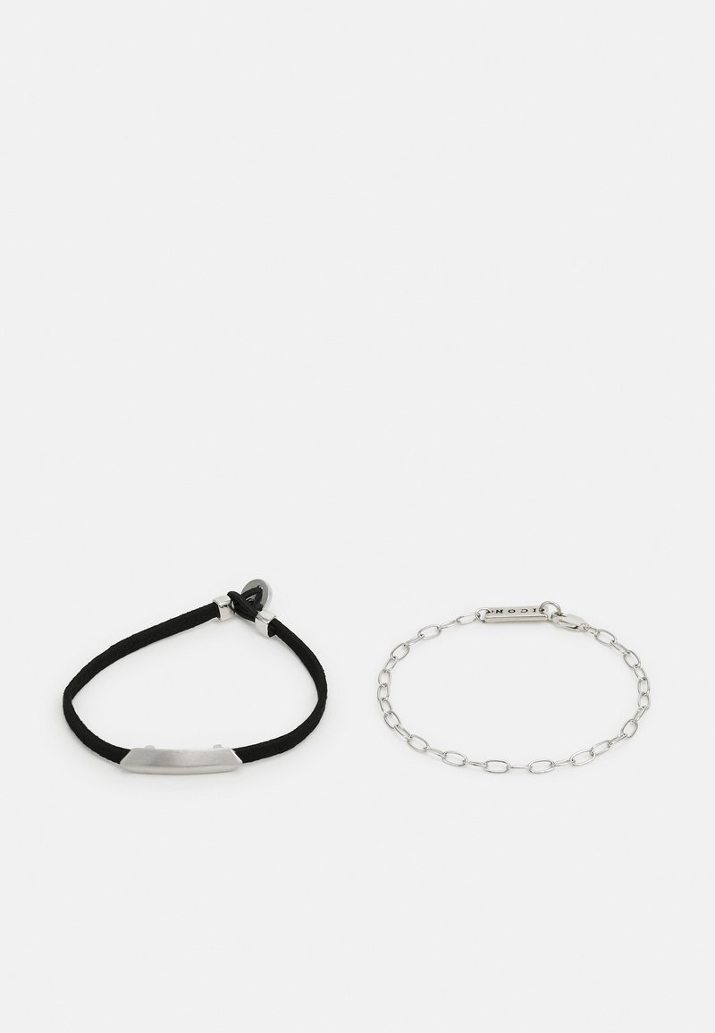 Bracelet en cordon noir avec une plaque métallique rectangulaire lisse et bracelet en chaîne en argent avec une étiquette rectangulaire.
