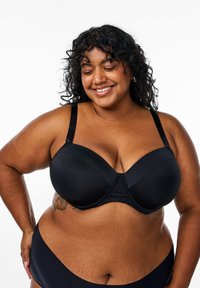 Black underwire bra with smooth finish, molded cups, adjustable straps, and seamless design. Close-fitting shape and matte texture.