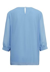 Helles blaues Blusenshirt mit Dreiviertelärmeln, versehen mit einem Schlüsselloch-Ausschnitt im Rücken und gepunkteten Akzenten am Bündchen. Glattes Material und lockere Passform.