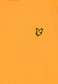 Short-sleeve, round-neck t-shirt in vibrant orange, featuring a small black and yellow embroidered bird logo on the left chest.