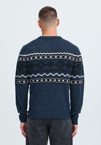 Pulover bleumarin cu un bandă orizontală modelată albă, neagră și gri în partea superioară, cu manșete și tiv cadrilat.