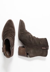 Botas de tobillo de ante marrón con diseño recogido, punta afilada, cremallera lateral y tacón apilado con textura acanalada.