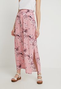Langer, rosa Blumenkleid mit einer lässigen Passform, einem elastischen Bund, seitlichen Schlitzen und einer weichen Textur, verziert mit weißen und lila Blumen.