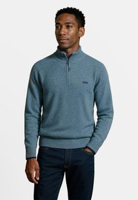 Gebreide blauwe pullover met hoge kraag en half-rits, voorzien van een textuurpatroon en geribde manchetten en zoom.