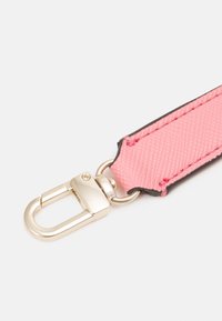 Różowy, teksturowany pasek materiałowy przymocowany do srebrnego metalowego haka obrotowego na białym tle.