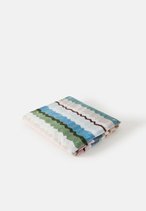 Tessuto piegato con strisce a zigzag orizzontali in verde, blu, bianco e marrone su sfondo bianco.