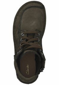 Zapato de cuero marrón con punta redonda, diseño de cordones y superficie texturizada. Nombre de la marca "Clarks" impreso en el interior.