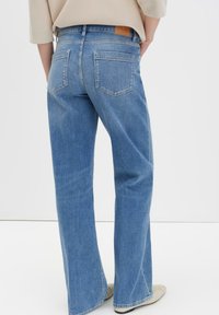 Lichtblauwe denim jeans met een rechte pijp, voorzien van twee achterzakken en een tan leren label op de tailleband.