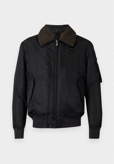 Blouson bomber noir avec col en shearling marron doux, fermeture éclair frontale, deux poches latérales et poignets et ourlet côtelés.