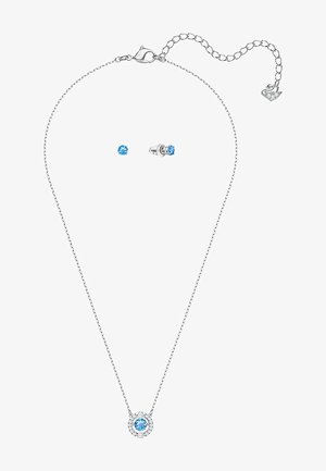 Srebrny naszyjnik z okrągłym niebieskim wisiorkiem otoczonym mniejszymi białymi kamieniami, w zestawie z pasującymi niebieskimi kolczykami wkrętami. Łańcuszek ma regulowane zapięcie.