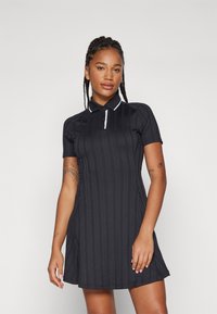 Musthave lühikese varrukaga polo kleit vertikaalse ribakujundusega, valge krae ja õmblused. A-line kuju ja kaks küljetaskut, argine disain.