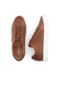 Baskets en cuir marron avec une semelle en caoutchouc blanche, dotées d'un bout rond, d'un laçage à l'avant et de détails de couture sur le côté.