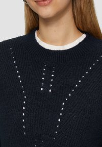 Marine gebreide sweater met een ronde hals, een textuurpatroon en kleine uitsparingen in een verticale indeling.
