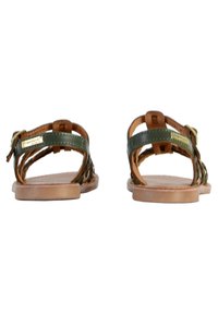 Bruine en groene gevlochten leren sandalen met een platte zool en enkelschoenen; heeft een gouden logo-accent aan de zijkant en een open achterkant.