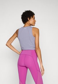 UJDNÉLT KÉK PULÓVER, ZÖLD TORNACIPŐVEL; AZ ÖLTÖZET KIEGÉSZÍTÉSE MÓDOSÍTOTT DLOGÚRAL BETÉTEKKEL. 