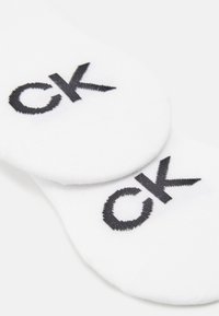 Bijele pamučne čarape s crnim izvezenim "ck" logotipom. Nizak kroj, meka tekstura s glatkom završnom obradom i ojačano područje prstiju.