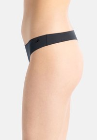 Zwarte stringonderbroek met een soepel, minimalistisch ontwerp en een lage tailleband. De stof lijkt rekbaar en comfortabel te zijn.