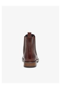 Botas de tobillo de cuero marrón con paneles laterales elásticos, puntera redondeada y tacón apilado. Con un tirador en la parte posterior para facilitar su puesta.