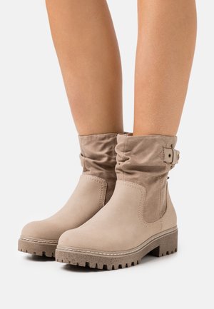 Beige enkellaarsjes van zacht suède met een geplooid ontwerp, voorzien van een zijgesp detail en een gestructureerde rubberen zool.