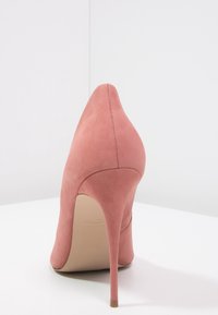 Escarpin en daim rose à bout pointu et silhouette épurée. Caractérisé par un talon aiguille fin et des détails de couture soignés.
