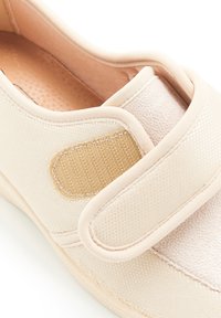 Scarpa beige slip-on con tomaia in tessuto testurizzato, dotata di una grande fascia regolabile in Velcro e una soletta imbottita. Suola in gomma liscia.