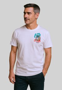 Witte katoenen t-shirt met een kleurvolle "Pizza Club" graphic met afbeeldingen van koekjes en pizza, korte mouwen en een ronde halsontwerp.